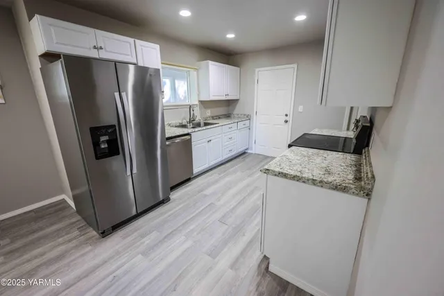 a kitchen with granite countertop a refrigerator and a sink