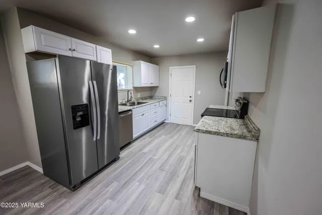 a kitchen with stainless steel appliances granite countertop a refrigerator a stove and a wooden floors