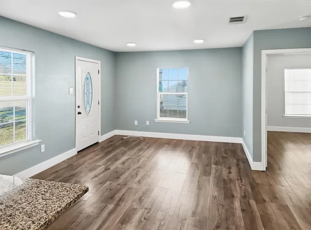 an empty room with wooden floor and windows