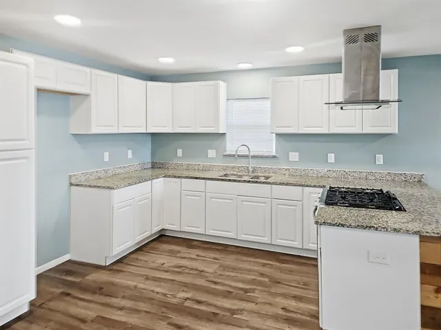 a kitchen with granite countertop a sink stove and cabinets