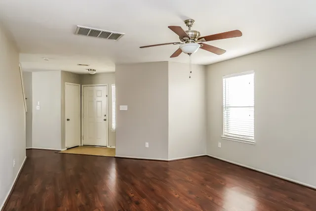 a view of an empty room with wooden floor and a window