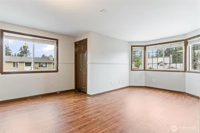 a view of an empty room with a window and wooden floor