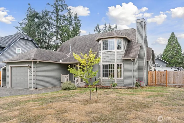 a view of a house that has a small yard and large tree
