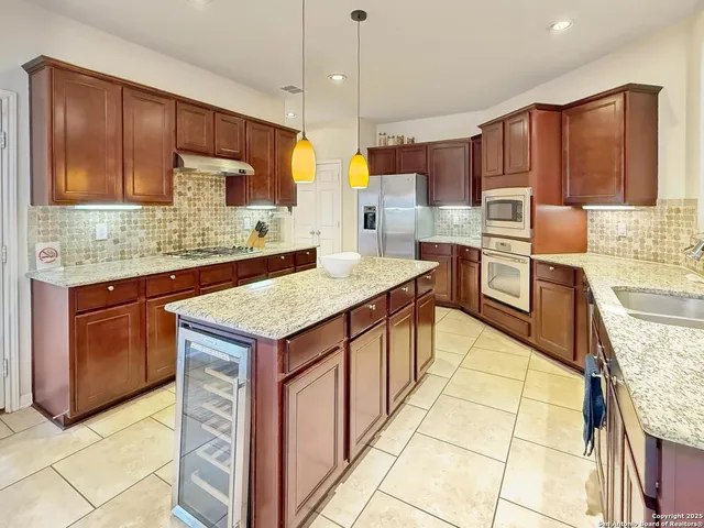 a kitchen with granite countertop a sink a counter top space appliances and cabinets