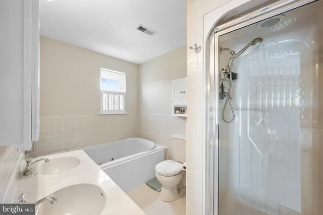 a bathroom with a toilet sink vanity tub and shower