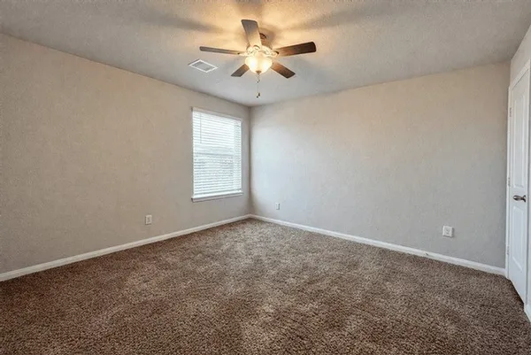 an empty room with windows and chandelier fan