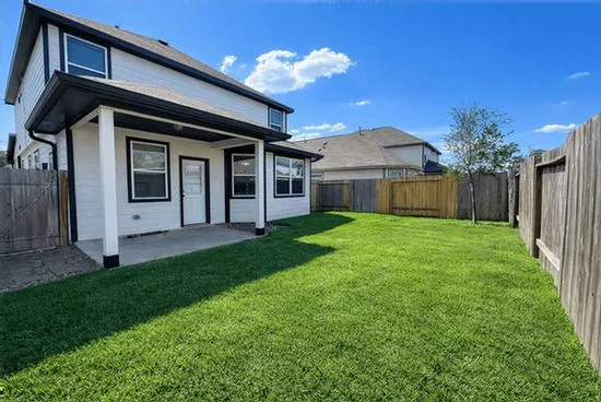 a view of a house with a yard plants and large tree