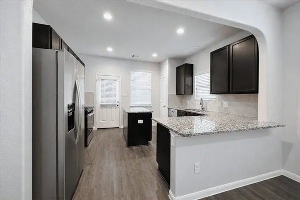 a large kitchen with a sink a counter top space stainless steel appliances and cabinets