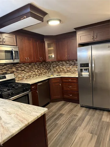 a kitchen with stainless steel appliances granite countertop wooden cabinets a refrigerator and a sink