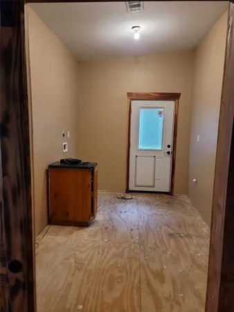 an empty room with wooden floor and entrance