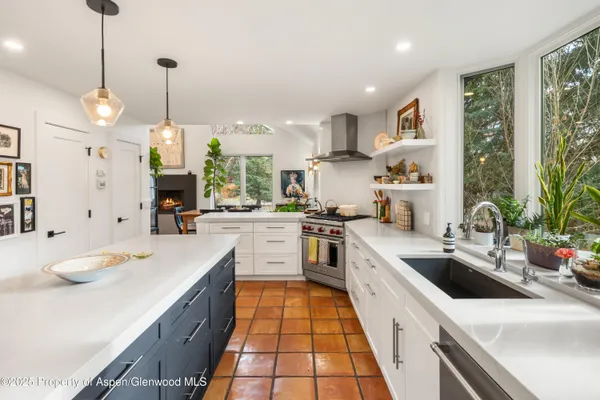 a large kitchen with kitchen island a large counter space a sink appliances and a large window