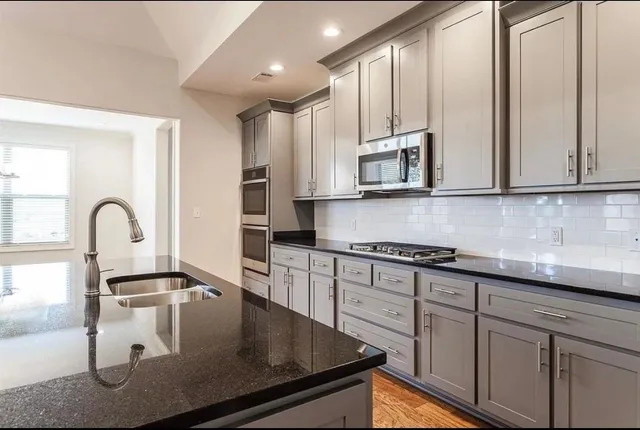 a kitchen with stainless steel appliances granite countertop a sink a stove and cabinets