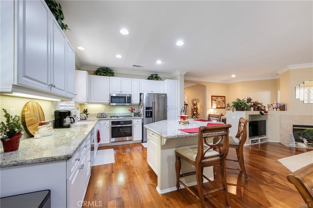 27956 Crystal Spring Drive Menifee, CA 92584 - Photo 9 of 25 a kitchen with stainless steel appliances granite countertop a stove top oven a sink dishwasher a dining table and chairs with wooden floor