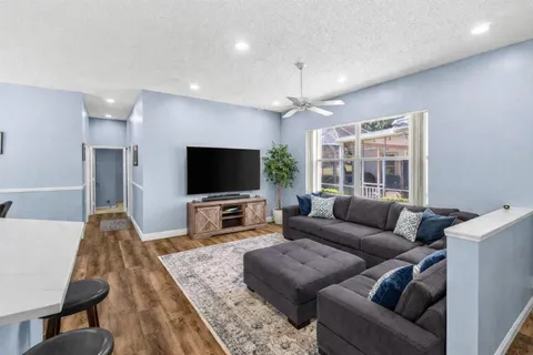a living room with furniture kitchen view and a wooden floor
