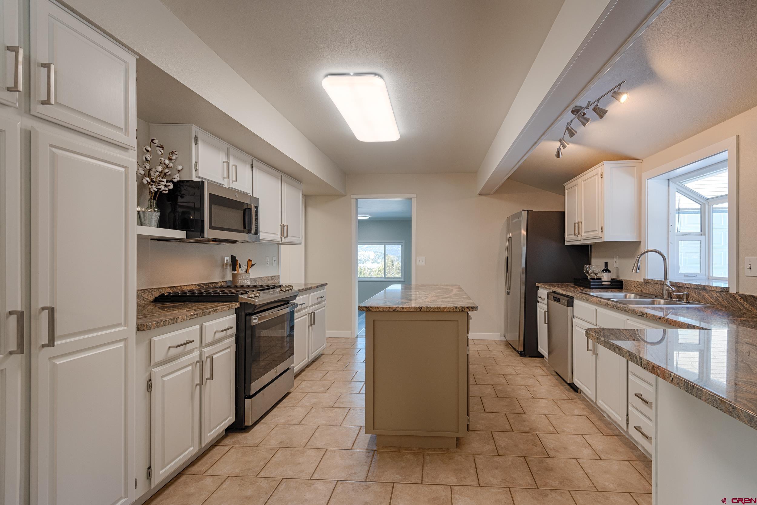 711 Terrace Drive Ridgway, CO 81432 - Photo 8 of 32 a large kitchen with stainless steel appliances granite countertop a stove top oven a sink dishwasher a refrigerator and a oven with white cabinets