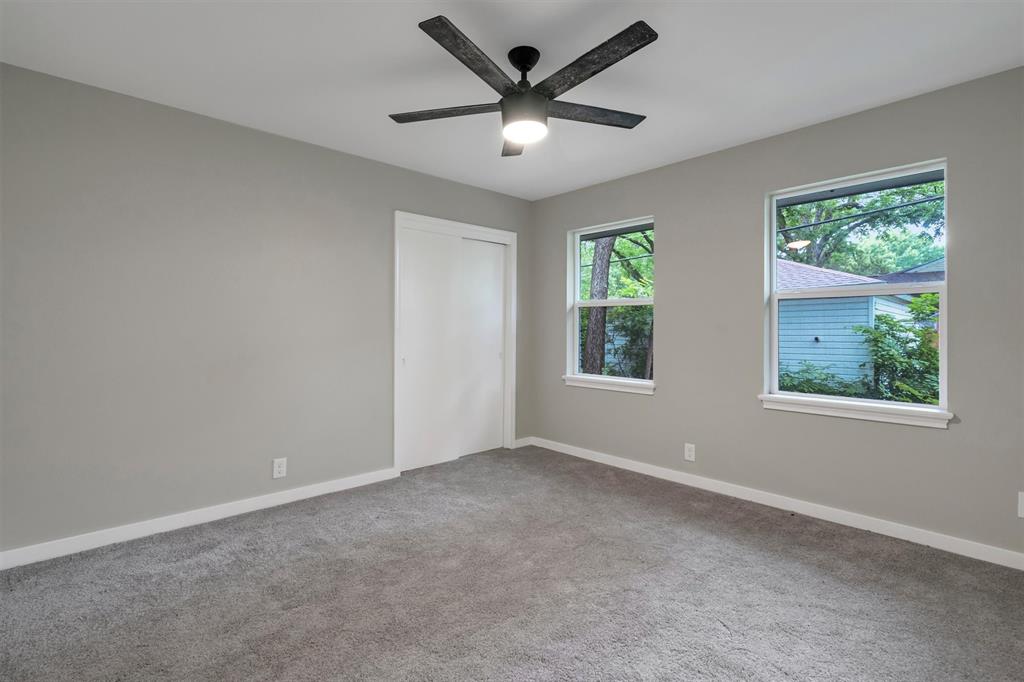 4815 Kelman Street Dallas, TX 75214 - Photo 27 of 37 Neutral gray walls accentuating a ceiling fan with integrated lighting, two windows, and gray carpeting