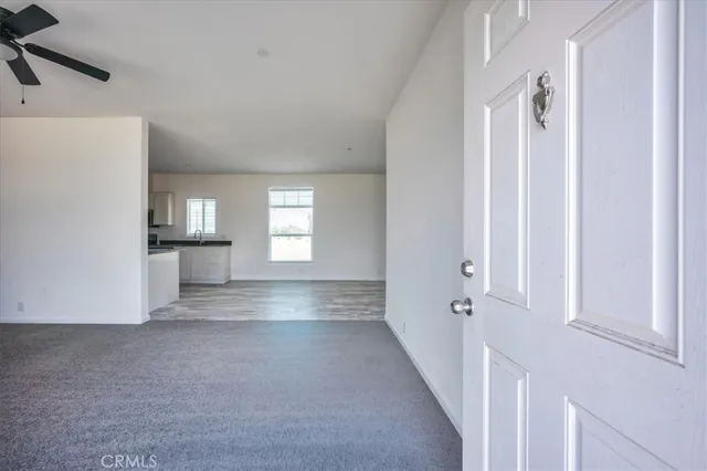 a view of an empty room with a window and a kitchen