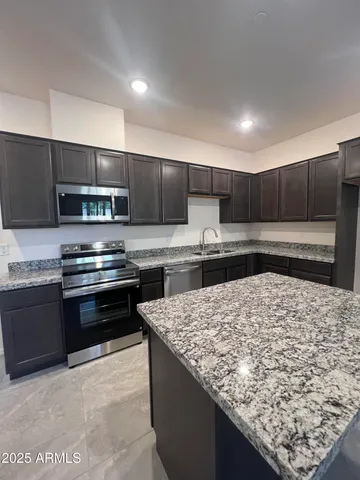 a kitchen with kitchen island granite countertop a sink stove and refrigerator