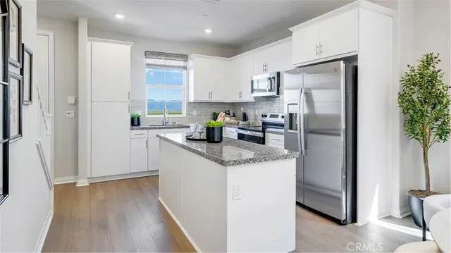 a kitchen with stainless steel appliances granite countertop a refrigerator a sink a stove a washer and dryer