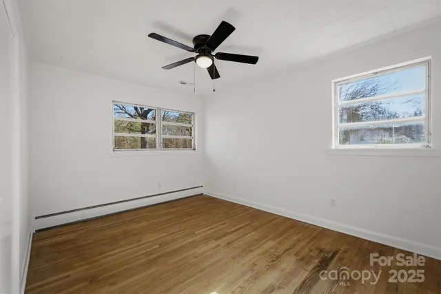 a view of a big room with wooden floor and windows