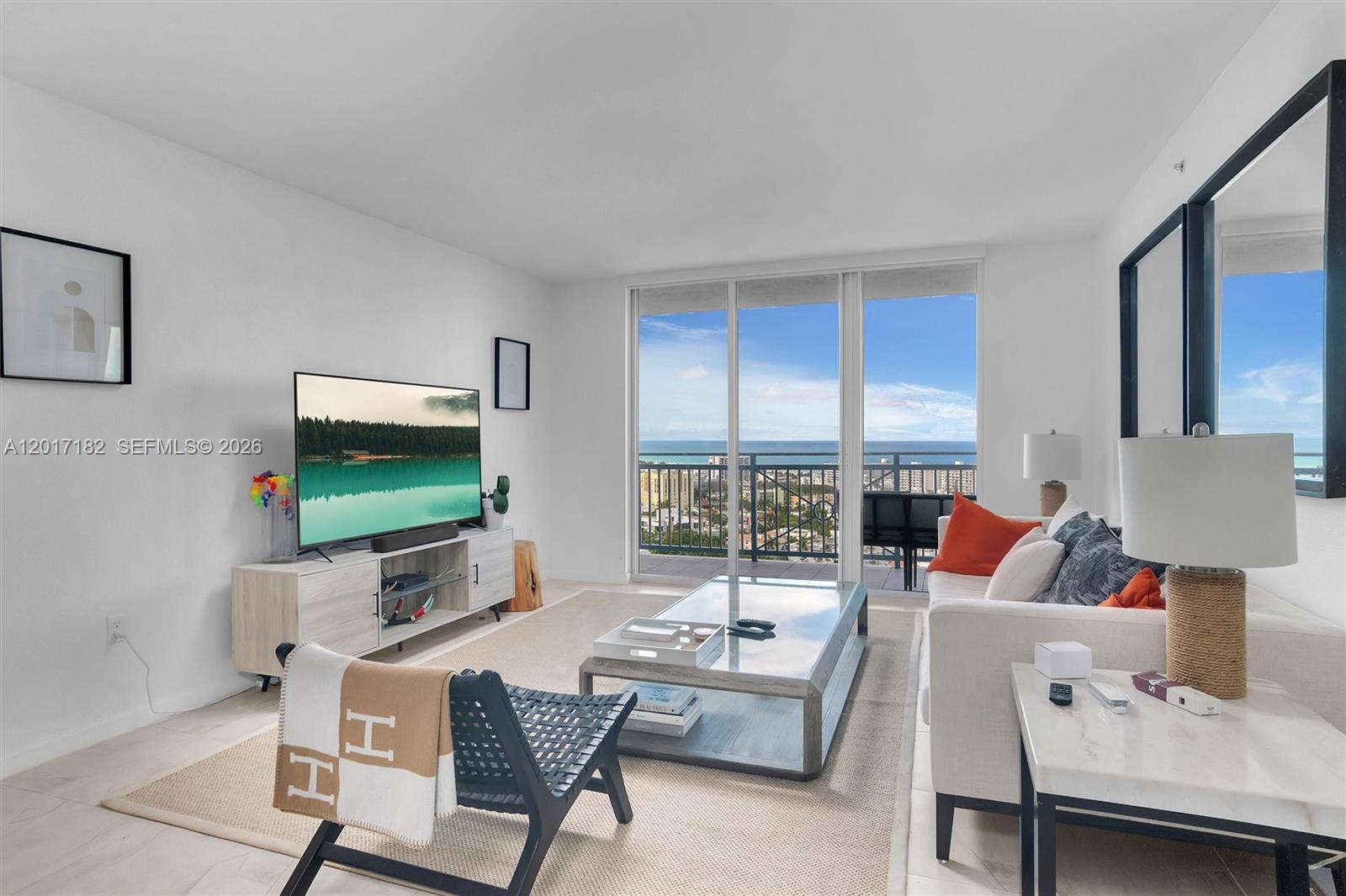 90 Alton Road, Unit 2303 Miami Beach, FL 33139 - Photo 3 of 29 a living room with furniture a flat screen tv and a floor to ceiling window