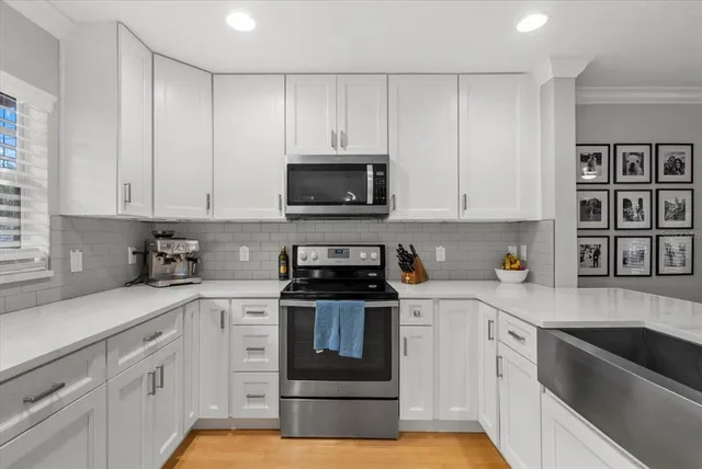 a kitchen with granite countertop white cabinets and stainless steel appliances
