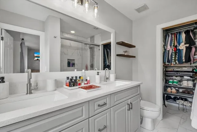 a bathroom with a sink a toilet and a large mirror