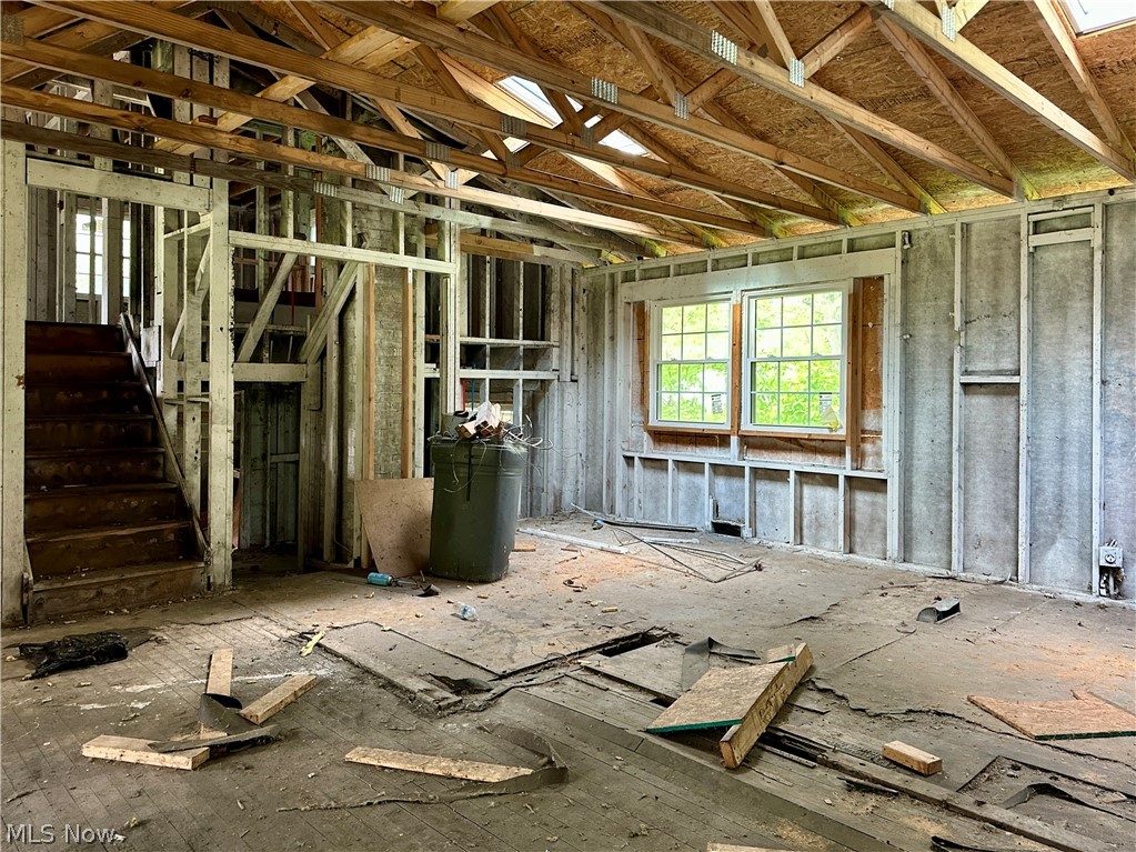 5319 Fairtree Road Bedford Heights, OH 44146 - Photo 9 of 27 Interior space with visible ceiling trusses, exposed wall studs, and a wood staircase