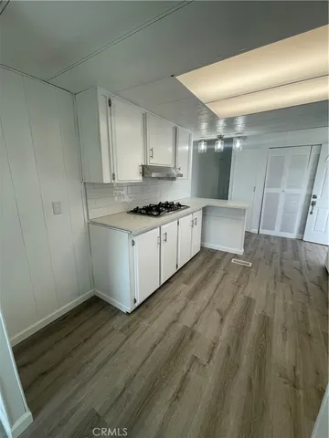 a kitchen with stainless steel appliances wooden floors and white walls