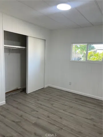 a view of an empty room with wooden floor and windows