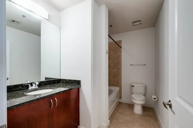 a bathroom with a granite countertop sink toilet and shower
