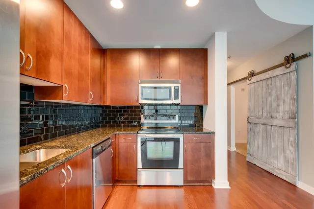 a kitchen with stainless steel appliances granite countertop a refrigerator a stove and a wooden floors