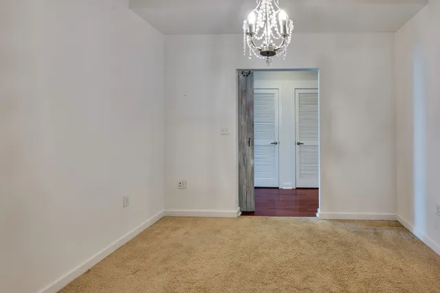 an empty room with a chandelier fan and wooden floor
