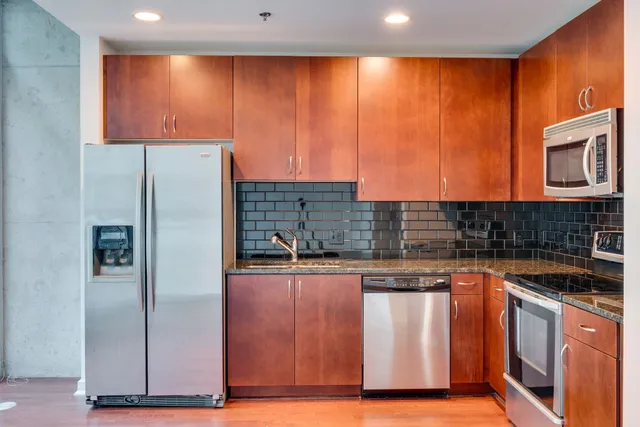 a kitchen with stainless steel appliances granite countertop a refrigerator and a stove