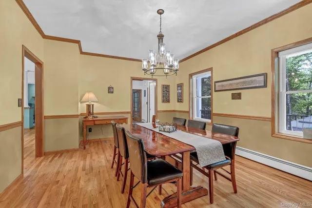 a dining room with wooden floor a chandelier a wooden table and chairs