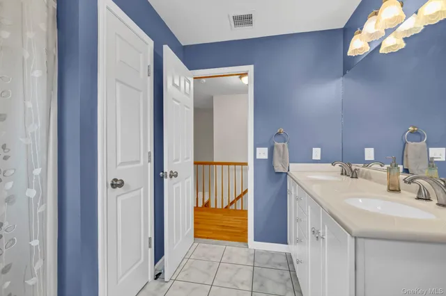 a spacious bathroom with a double vanity sink a toilet and a mirror