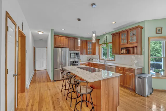 a kitchen with stainless steel appliances granite countertop wooden floor window and refrigerator