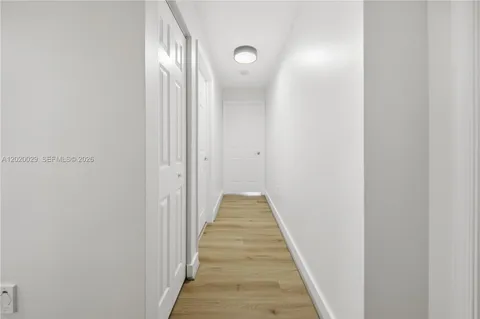 a view of a hallway with wooden floor and a bathroom