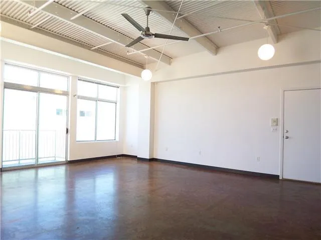 an empty room with wooden floor and windows with curtains