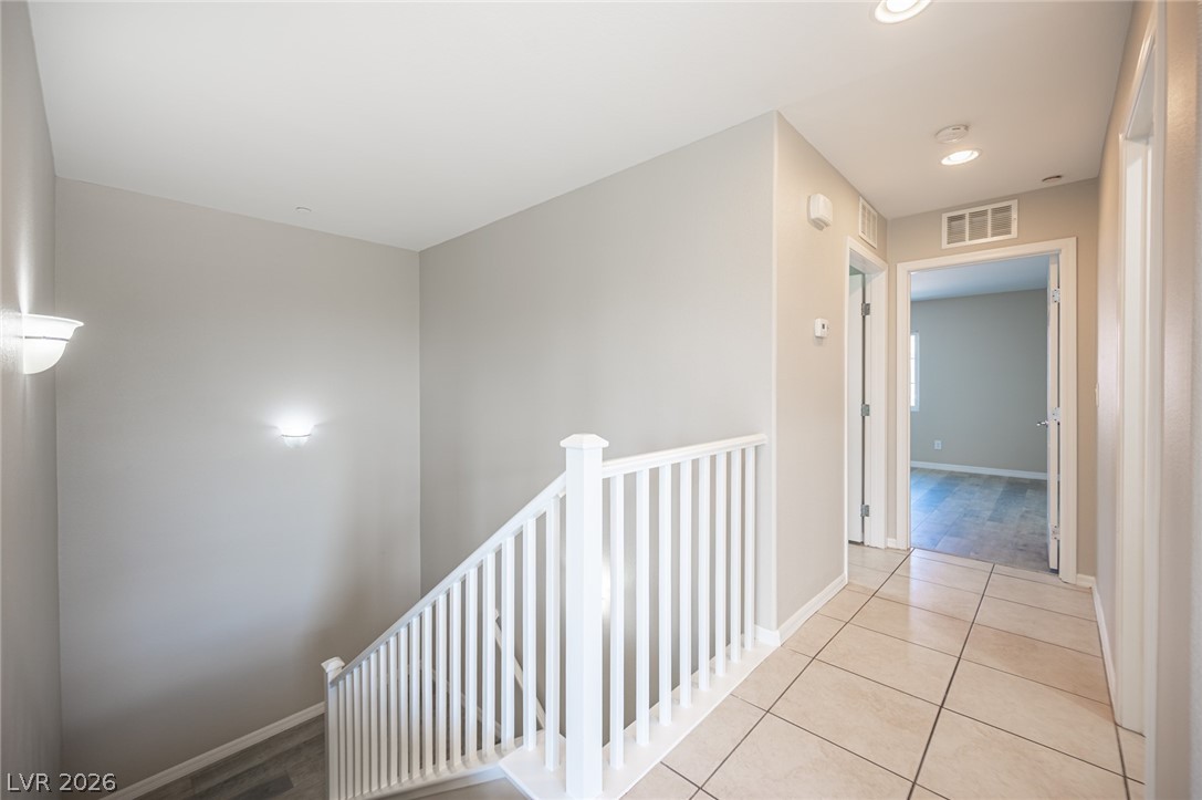 9916 Sable Point Street Las Vegas, NV 89178 - Photo 25 of 73 A graceful staircase with a crisp white railing ascends, complementing the hallway's tiled flooring.