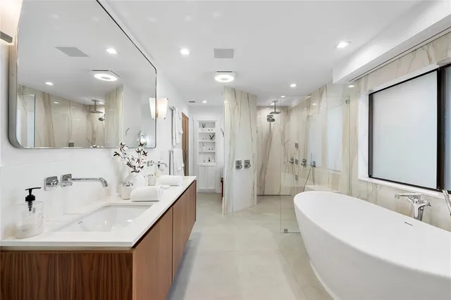 a bathroom with a bathtub shower sink mirror and toilet