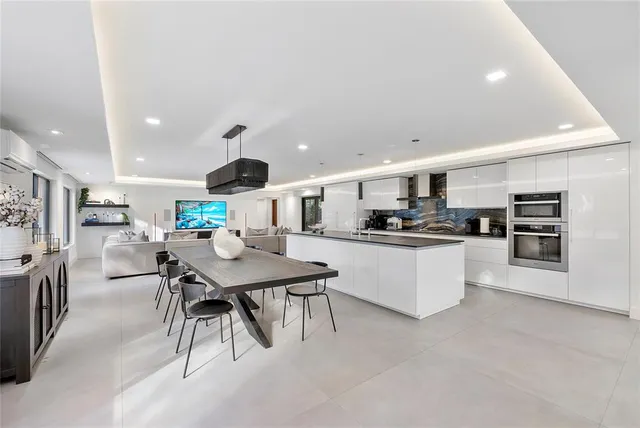 a kitchen with stainless steel appliances kitchen island granite countertop a refrigerator a stove a sink a dining table and chairs with wooden floor