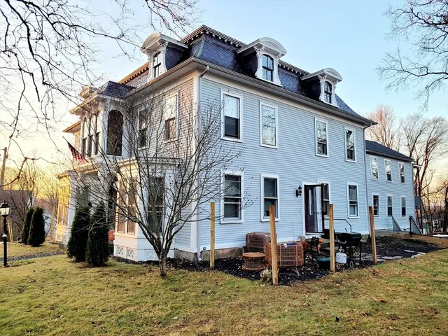 a view of a house with a yard chairs and a tree