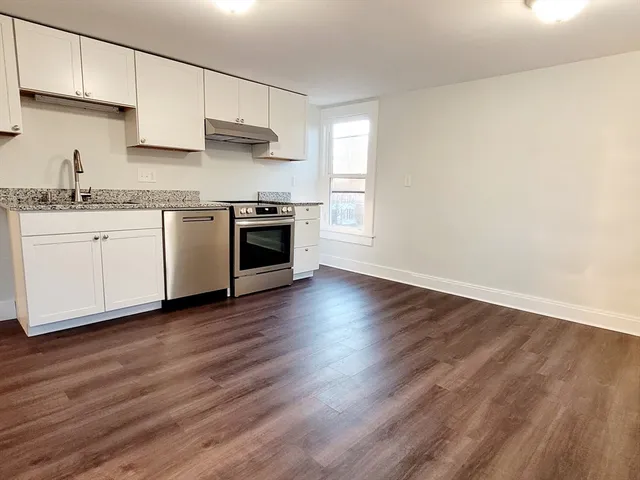 a kitchen with granite countertop a sink cabinets and stainless steel appliances