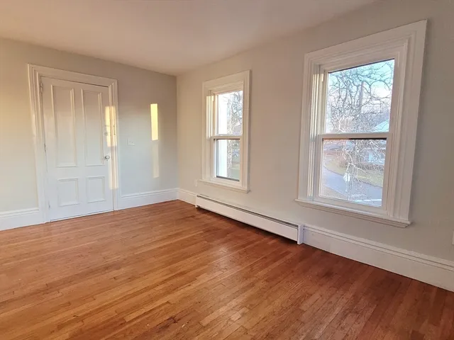 a view of an empty room with wooden floor and window