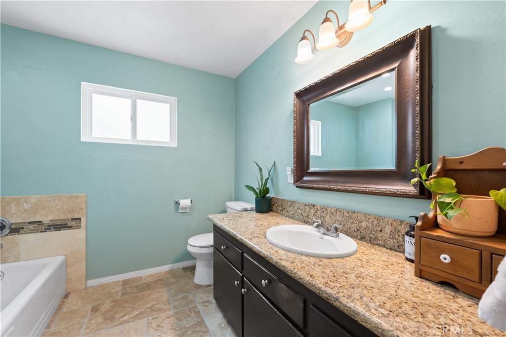 24405 Derian Drive Newhall, CA 91321 - Photo 26 of 44 a bathroom with a granite countertop sink a toilet and mirror