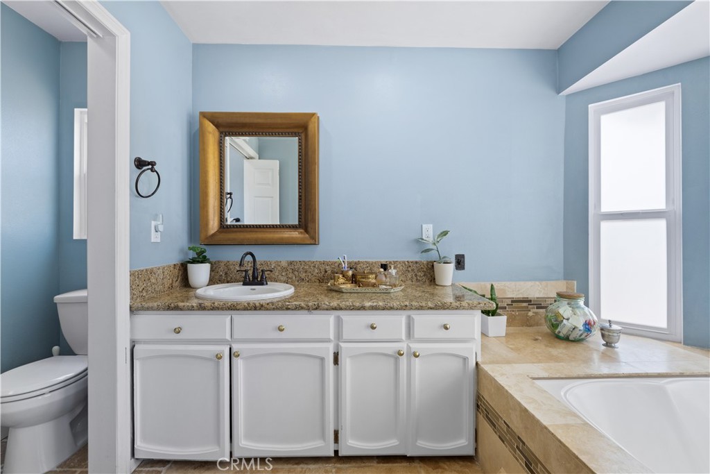 24405 Derian Drive Newhall, CA 91321 - Photo 31 of 44 a bathroom with a granite countertop sink a mirror and a toilet