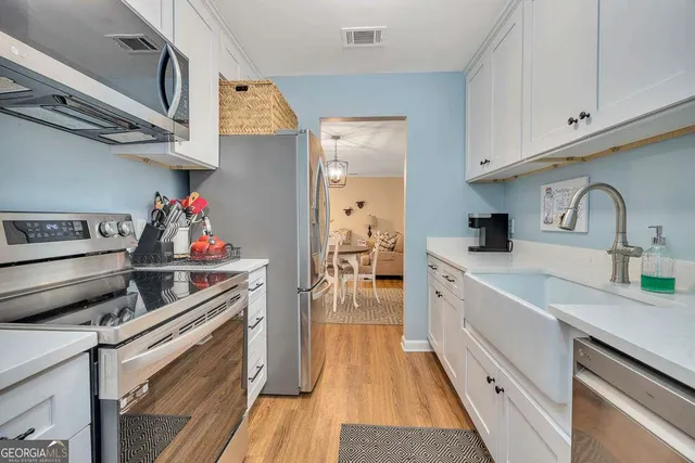 a kitchen with kitchen island wooden floors appliances and cabinets