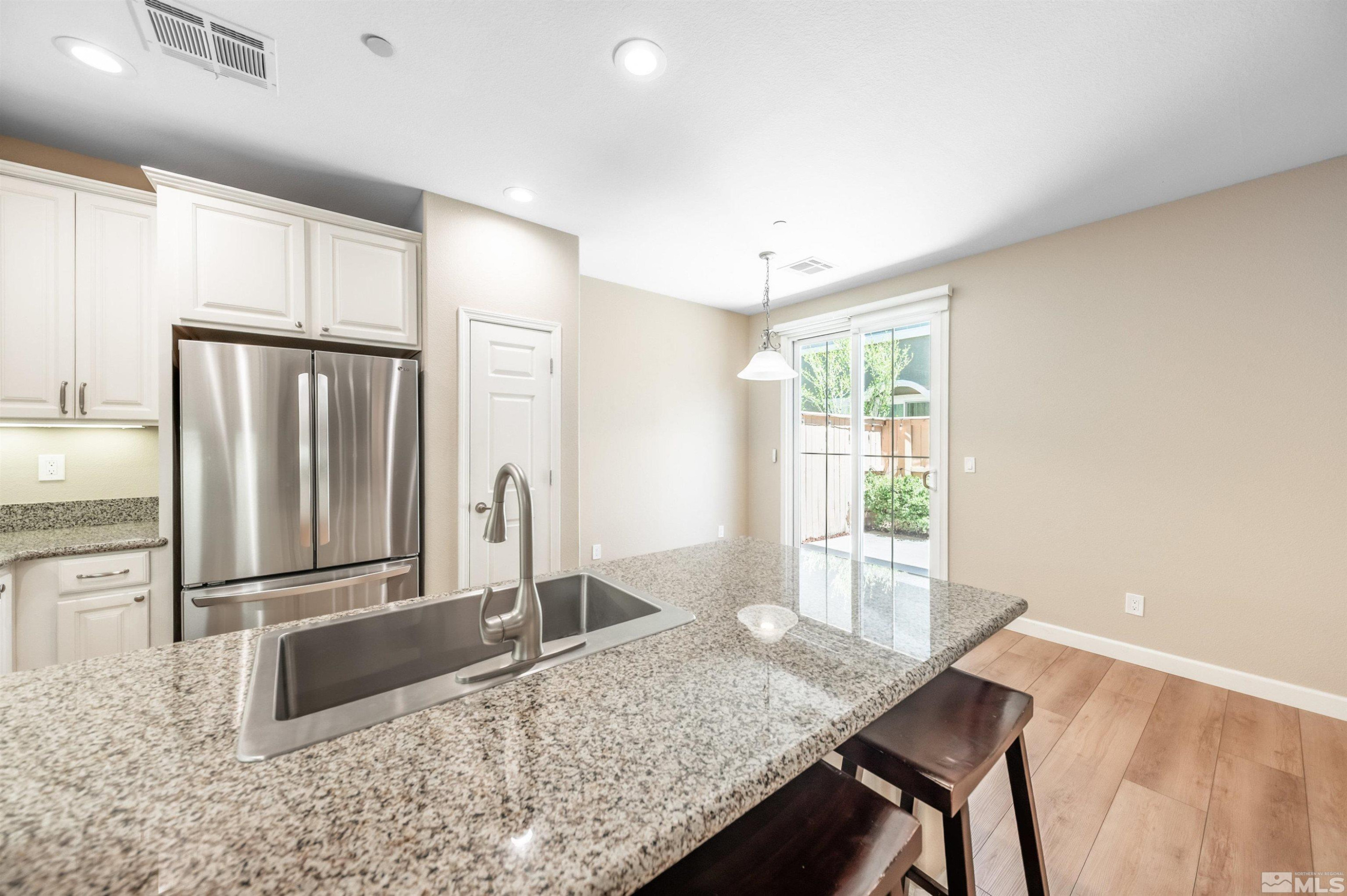 1835 Wind Ranch Road, Unit B Reno, NV 89521 - Photo 10 of 38 a kitchen with granite countertop a refrigerator and wooden cabinets
