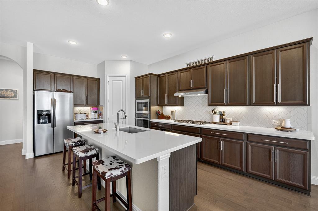 1420 Wolf Ridge Run Gunter, TX 75058 - Photo 28 of 40 a kitchen with stainless steel appliances a sink a stove a refrigerator and cabinets